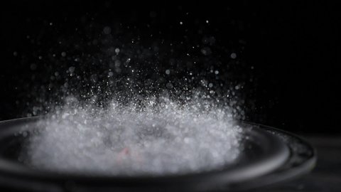 Trembling loudspeaker throwing silver flour in the air. Super slow motion close-up shot.