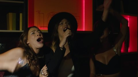 girls having fun and singing karaoke in a nightclub