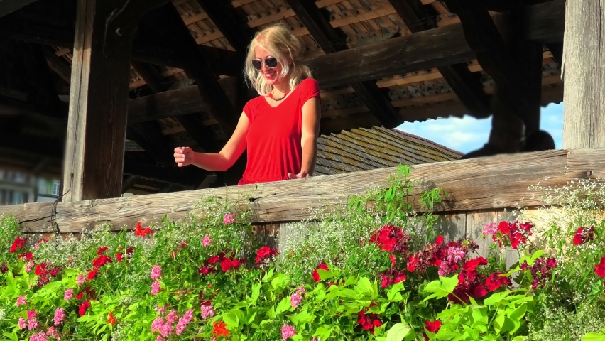 Close up on a blonde girl in red on the flowery bridge of Lucerne city, Reuss river in Switzerland. Chapel Bridge: historic covered wooden pedestrian bridge, the most famous landmark of Lucerne town.