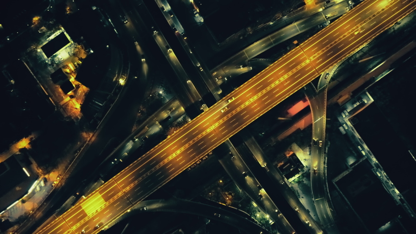 Top down night city roads with cars driving aerial view. Nightly urban cityscape with modern skyscrapers. Majestic cityscape lit by neon lanterns lights with traffic highway. Cinematic vehicle scenery