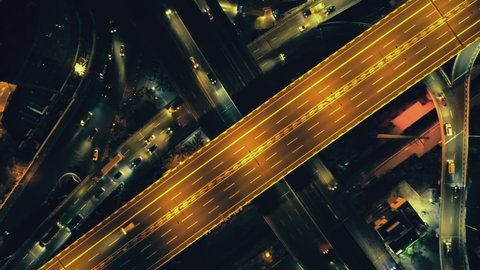 Top down night city roads with cars driving aerial view. Nightly urban cityscape with modern skyscrapers. Majestic cityscape lit by neon lanterns lights with traffic highway. Cinematic vehicle scenery