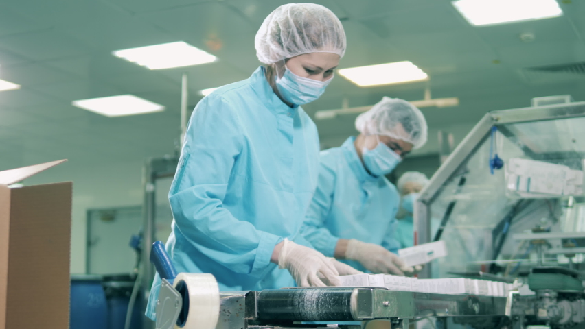 Asian ethnicity workers put pills into boxes at factory. Pharmaceuticals production line at a modern pharmaceutical facility. Royalty-Free Stock Footage #1060635832