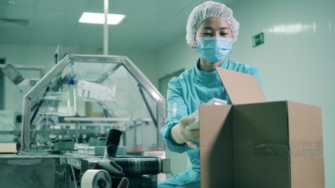 Asian ethnicity laboratory worker packs tubes into boxes.