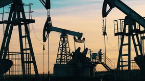 Oil worker standing among the oil pump jacks. Oil industry, crude oil prices concept. - Powered by Shutterstock - Get 15% off with code: PIKWIZARD15