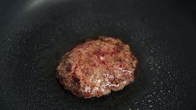 Hamburger meat patty frying on hot pan in kitchen at home