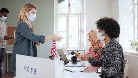 People with face masks voting in polling place, usa elections and coronavirus.
