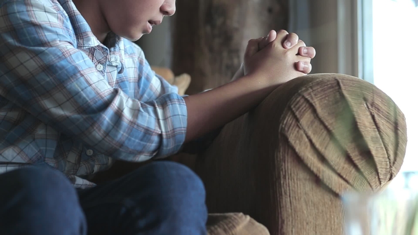 Boy praying on sofa at home, church in home, Home church during quarantine coronavirus Covid-19, Religion concept. Royalty-Free Stock Footage #1060642153