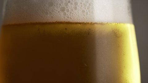 Cold beer with foam in the glass, rotate, close up.