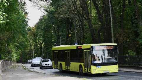 Lviv, Ukraine - 10 07 2020: Time lapse of car traffic transportation on old cobblestone paved road and people walk by pedestrian crossing to city bus stop. Commuter transport in European town