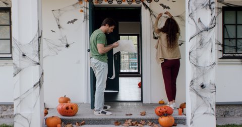 Caucasian couple of family decorating their house for Halloween celebration. Applying bat wall stickers. Shot on RED cinema camera with 2x Anamorphic lens