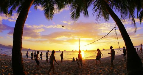 BORACAY, PHILIPPINES 9 FEB 2015: Unidentified volleyball players enjoy warm sunset time and play ball on tropical sandy beach. Lifestyle activity background