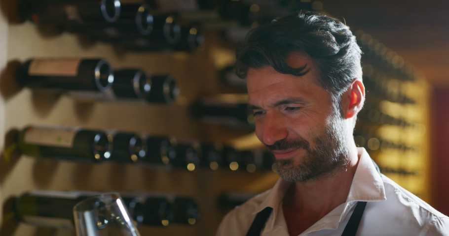 Authentic shot of successful male sommelier is tasting a flavor and checking white wine quality poured in transparent glass in a wine cellar. Royalty-Free Stock Footage #1060657852