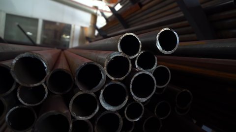 Modern industrial plant for the production of small diameter pipes. Warehouse space. Pile of steel pipes at a factory for the production of pipes for pouring, close-up, 4k