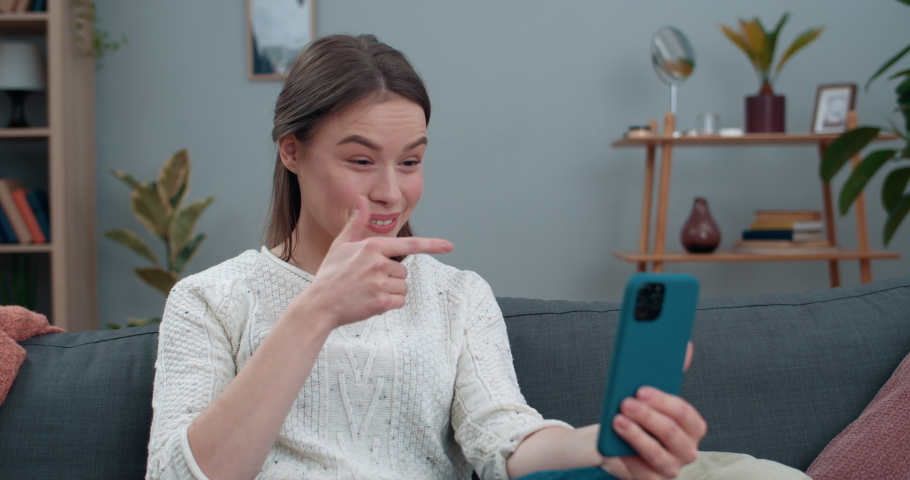 Cheerful deaf woman having video call and showing with sign language Hello, how are you Female pretty person smiling and using smartphone for communication. Concept of hear loss | Shutterstock HD Video #1060658800