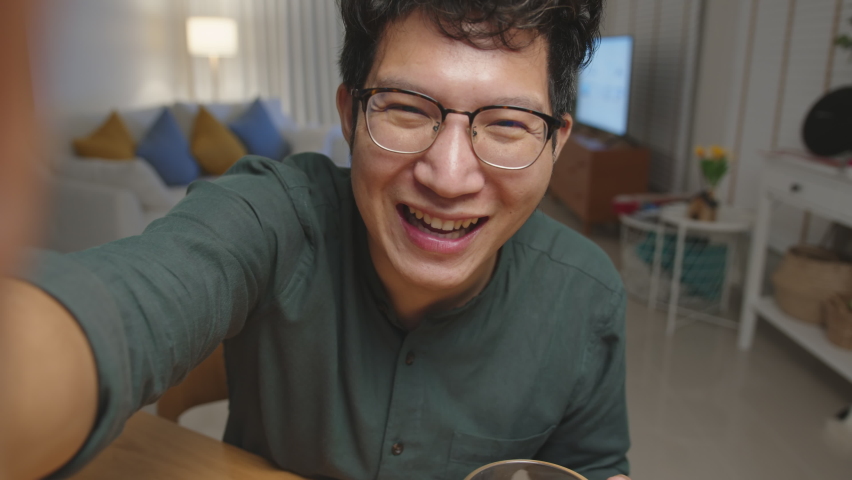 POV screen mobile: Attractive young happy asian man enjoy relax night party event online celebration festive with friends at house clinking beer with glass and bottle toasting drinking via video call. Royalty-Free Stock Footage #1060661509