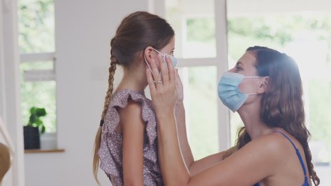 Mother And Daughter Putting On Face Masks Before Leaving Home