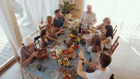 High angle view of large multigenerational family sitting together at table, putting food on plates and pouring drinks into glasses while having holiday dinner at home - Powered by Shutterstock - Get 15% off with code: PIKWIZARD15