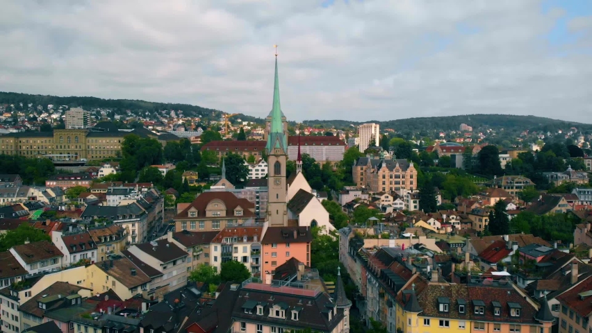 Drone shot slowly around the Predigerkirche church and the Niederdorf district of Zurich city, partly sunny, summer day, in Switzerland - orbit, aerial view