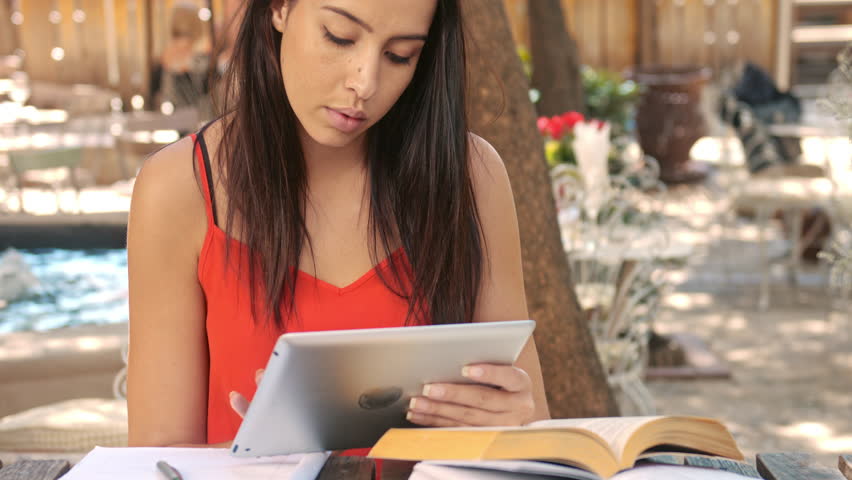 4k medium shot of casually dressed woman student with tablet computer doing homework at wifi internet coffee cafe., a Technology Video by Milk Image-a Films