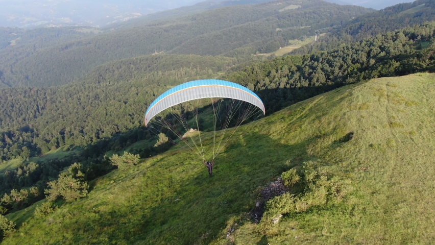 Tracking Aerial View of Paragliding Pacarhute Flying Above Green Mountain Hills. Zlatibor, Serbia. Summer Activity and Adrenaline Concept, Drone Shot Royalty-Free Stock Footage #1060667860