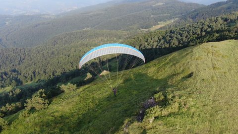 Tracking Aerial View of Paragliding Pacarhute Flying Above Green Mountain Hills. Zlatibor, Serbia. Summer Activity and Adrenaline Concept, Drone Shot