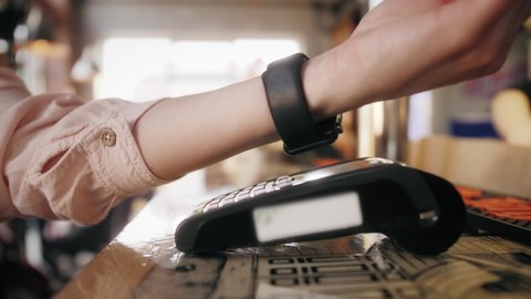Customer paying with an NFC contactless smartwatch with a card machine. Paying in a coffee shop by a smartwatch. NFC Technology.