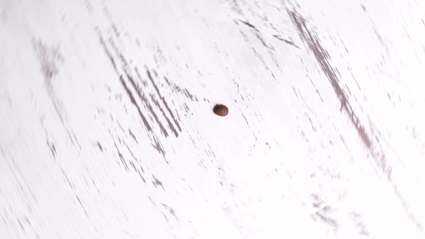 Top view of bunch of roasted coffee beans sliding and forming heart in middle of whirling surface