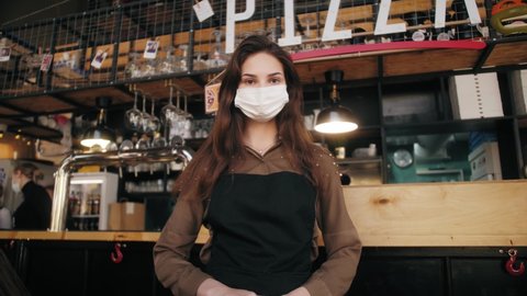 Portrait of owner woman cafe wearing face medical mask, Cafe staff working in protective masks. Owner pizzeria. New Life After Covid-19. Business reopen after coronavirus quarantine is over.