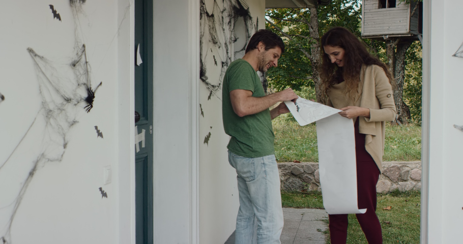 Caucasian couple of family decorating their house for Halloween celebration. Applying bat wall stickers. Shot on RED cinema camera with 2x Anamorphic lens