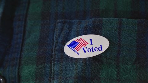 Man puts I Voted Sticker on Clothing After voting in American Democratic Election, doing one's civil duty
