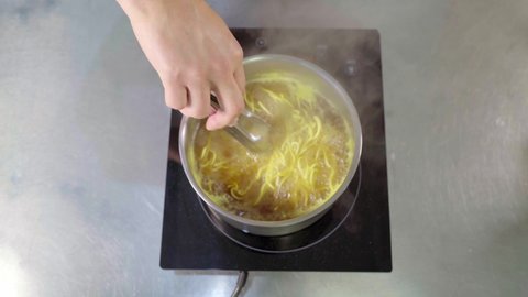 pouring ramen noodles into chicken broth