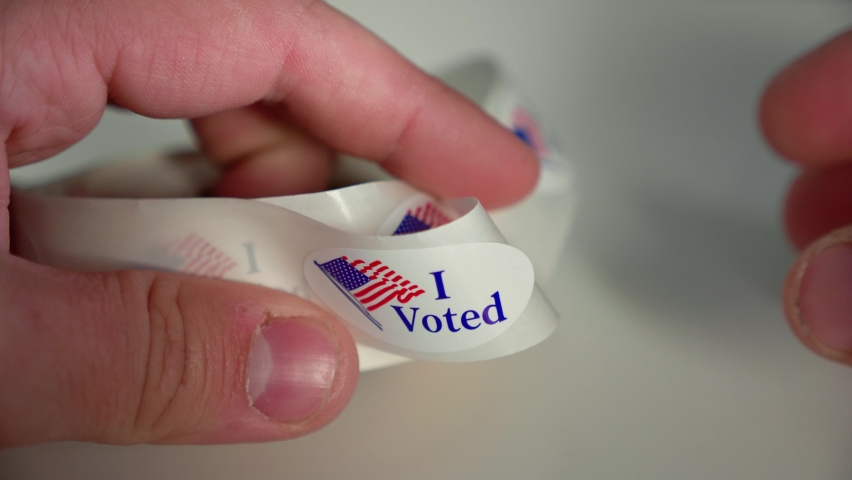 Close up shot of Man getting his I Voted sticker from a roll after voting in an American USA democratic election Royalty-Free Stock Footage #1060675927