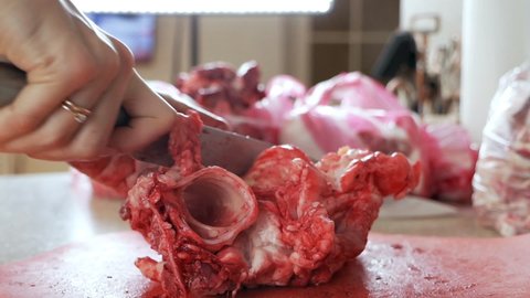 Human hands use a butcher's knife, which is used to cook and cut meat. Hands with a knife cut meat, pork covered in blood