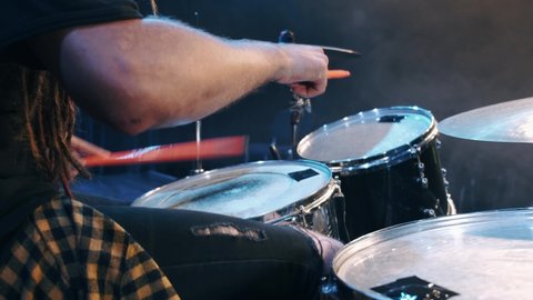 Musician is playing the drum set in the dark studio. Male Drummer playing drums in smoke.