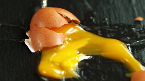 Super Slow Motion Shot of Falling and Breaking Whole Egg on Black Table at 1000 fps.