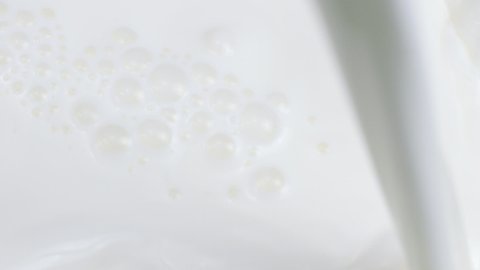 milk jet pouring on milk surface with waves, whirlpools and bubbles slow motion close up. Dairy products contain lot of calcium. Advertising intro for Cheese, curd, yogurt, butter production
