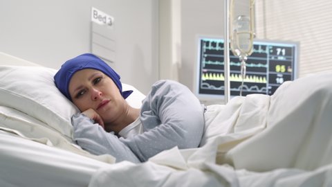 sad desperate terminal cancer ill female patient in the hospital bed,sick hopeless young woman wearing cancer hat headscarf