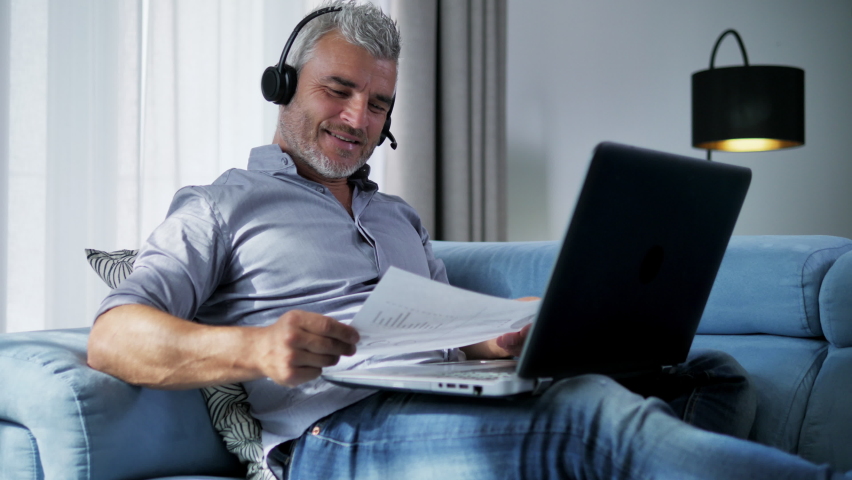 Smiling comfortable businessman on the couch enjoy working from home business video call,adult mature manager entrepreneur making distance conference using laptop webcam | Shutterstock HD Video #1060685293