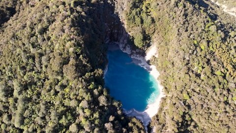 Turquoise hot spring, underwater geyser aerial reveal shot of Inferno Crater Lake and Lake Rotomahana. Jungle forested volcanic valley, New Zealand