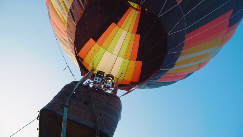 A hot air balloon taking off from a flat field, against the backdrop of a snowy cloudless sky. Royalty-Free Stock Footage #1060688458