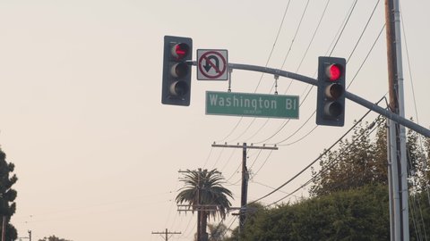Red traffic lights and no u-turns sign trun from red to green, on Washington Boulevard, overcast day, in Los Angeles, California, USA - Static view