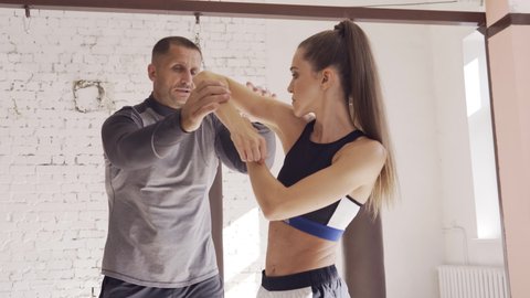 Cute girl learns kickboxing techniques in the gym with an experienced trainer