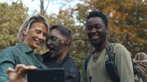 Happy young people in horror movie costumes taking selfie together