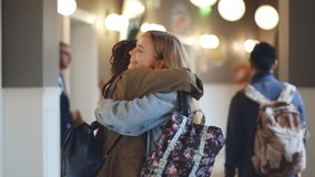 Two diverse female college classmates meeting and hugging in school corridor - Powered by Shutterstock - Get 15% off with code: PIKWIZARD15