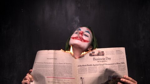 New York, USA - 12 October 2019: Joker Cosplay Actor Smoking and burning the New York Times Newspaper, Halloween Concept