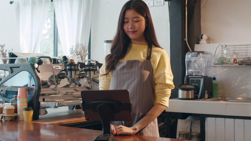 Young Asia female self service use mobile phone pay contactless with tablet at cafe restaurant. Girl barista talking receive orders from customer at bar counter in coffee shop. Owner small business. | Shutterstock HD Video #1060698730