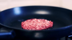 Fresh raw beef patty frying on pan in close up.Burger cutlet cooking in kitchen.Hamburger minced meat being fried for dinner meal in closeup 4K video clip.Uncooked pork grilling footage