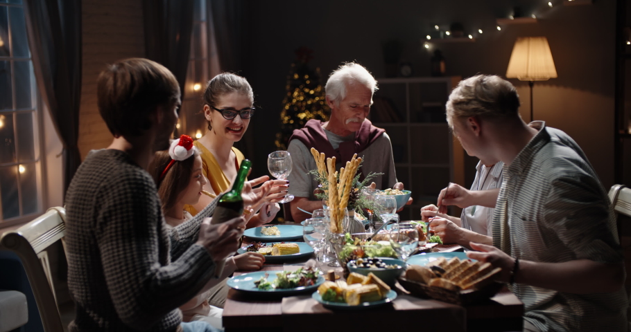 Happy large caucasian family of different generations celebrating christmas at home. People having a dinner xmas party eating, talking and smiling 4k footage | Shutterstock HD Video #1060702711