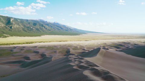 Colorado / United States - 10 09 2020: Man walking and lifting sand in The great sand dunes national park, sunny day, mountains in the background, in Colorado, USA - slow motion static view