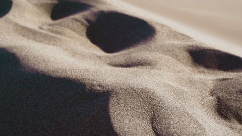 Footprints on sand dunes, sunny day, in Colorado, USA - handheld, slow motion, pan shot